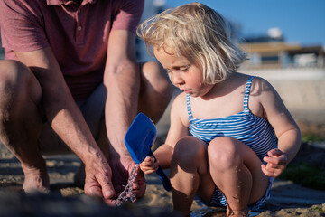 Little Girl Playing with Her Grandfather on the Beach During Summer Vacation