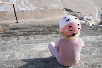  Little Girl in a Bike Helmet Sitting by the Stairs, Tired