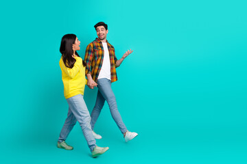 Obraz premium Joyful couple enjoying time together on turquoise background, holding hands and bonding in casual stylish outfits