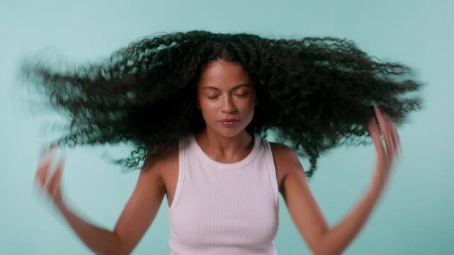 Model flips her long curly hair and does several expressive poses in front of a bright backdrop.