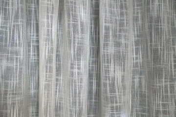 Texture of white translucent curtain with soft folds for monochrome textile background