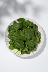 Fresh spinach leaves in bowl on white background for healthy eating