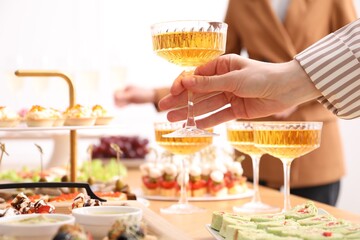 Buffet menu. Woman taking glass of sparkling wine from table, closeup