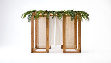 A simple sukkah with wooden frame and white curtains topped with green palm fronds on white background