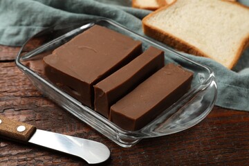 Tasty chocolate butter, slice of bread and knife on wooden table, closeup