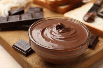 Tasty chocolate butter in bowl and pieces on table, closeup