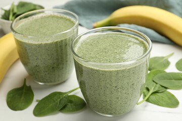 Tasty spinach smoothie and ingredients on white table, closeup