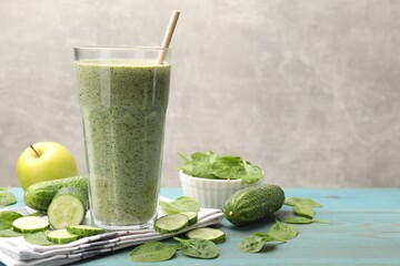 Tasty spinach smoothie and ingredients on light blue wooden table, closeup. Space for text