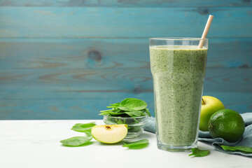 Tasty spinach smoothie and ingredients on white marble table, closeup. Space for text