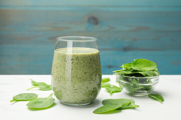 Tasty smoothie and spinach leaves on white marble table, closeup