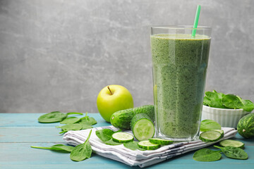 Tasty spinach smoothie and ingredients on light blue wooden table, closeup. Space for text