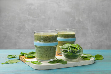Tasty spinach smoothie and ingredients on light blue wooden table