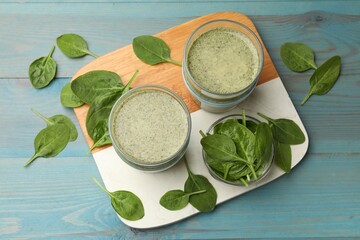 Tasty spinach smoothie and ingredients on light blue wooden table, flat lay