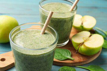 Tasty spinach smoothie and ingredients on light blue wooden table, closeup