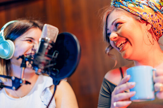 Two young women recording a podcast in a professional studio - Powered by Adobe