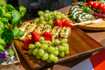 Appetizing snack platter with green grapes, fresh strawberries, and sesame-covered puff pastry...
