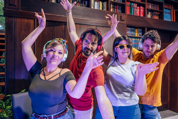 Friends dancing together at home wearing headphones and sunglasses