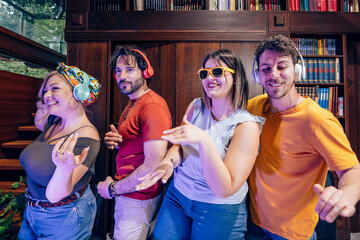 Friends dancing together and listening to music with headphones