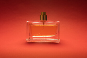 Stylish glass bottle of perfume on striking red background highlighting elegance and allure of...