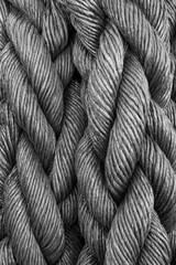 A close-up perspective reveals the intricate details of multiple gray ropes woven together,...