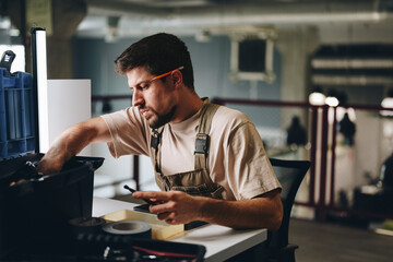 Craftsman working diligently at a table with tools in a modern workshop setting during daylight...