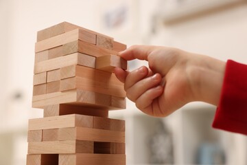Lviv, Ukraine - December 22, 2023: Little child removing wooden block from Jenga tower at home, closeup