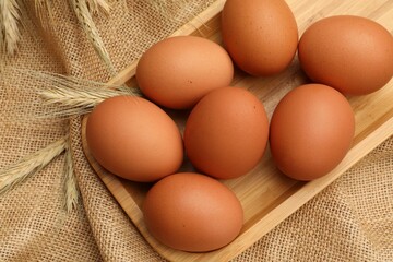Fresh eggs and spikes on burlap cloth, top view