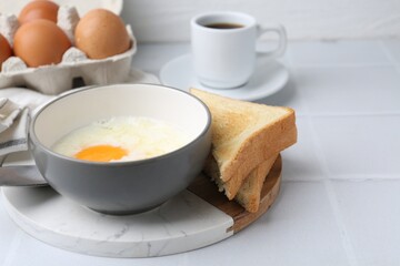 Traditional asian breakfast with half-boiled eggs in bowl, coffee and toasted bread on white tiled table, closeup. Space for text