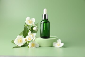 Cosmetic product and jasmine flowers on green background
