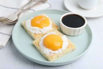 Tasty kaya toasts with half-boiled eggs served on white tiled table, closeup. Traditional asian breakfast