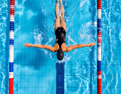 Top-down aerial view of a competitive swimmer doing butterfly stroke in an Olympic.