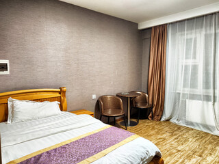 Cozy single room with wooden furnishings and natural light in a contemporary hotel setting