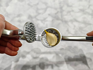 Efficiently pressing garlic with a stainless steel garlic press in a kitchen setting