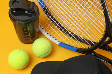 Tennis racket, sports bottle and ball on yellow background