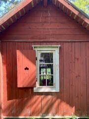 An old red plank wooden cottage. Finland. Red wood surface, weathered. White window
