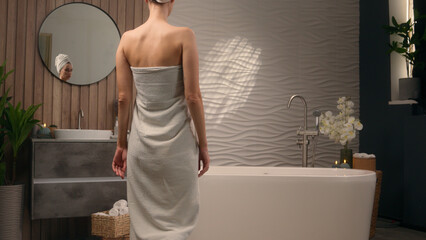 Back view Caucasian female woman lady girl wrapping in white cotton towel take off preparing for...
