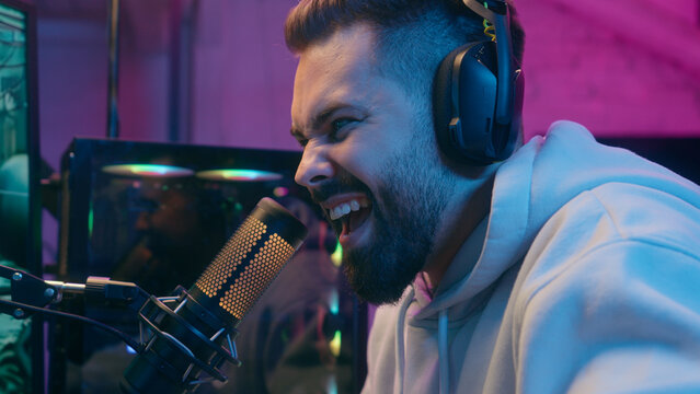 Caucasian millennial guy male gamer man streamer blogger vlogger influencer radio presenter in headphones studio streaming computer online video gaming cyber sport addict happy win achieve success