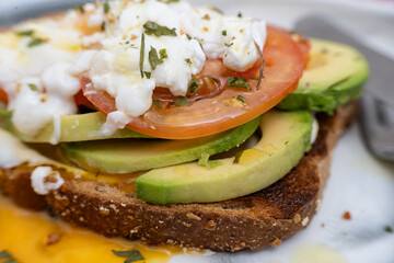 Poached egg, sliced avocado and tomato on toasted whole wheat bread