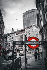London city street scene, black cabs in traffic, pedestrians walking, and distinctive modern architecture o]