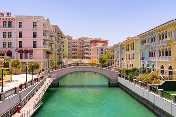 Picturesque view of Qatar, featuring pastel-colored Venetian-style buildings, arched pedestrian...