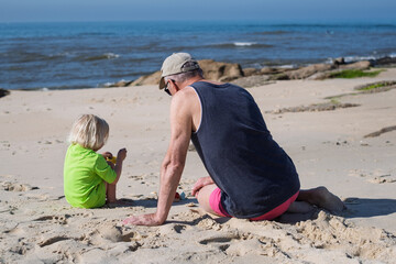 Grandfather Feeding His Granddaughter Watermelon on the Beach