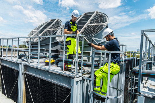 Professional worker servicing HVAC building cooling tower, Industry air conditioner service
