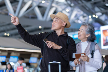 happy asian senior couple standing in the airport terminal,old woman holding passport and...