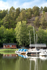 Small boats marina with motorboat and sailboats in a calm water bay in Swedish Stockholm...