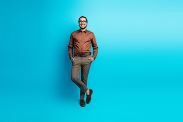 Stylish young professional man smiling in formal attire against a turquoise backdrop