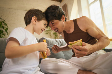 A father and his son share a leisurely Fathers Day meal inside, highlighting the themes of...