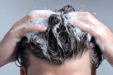 Naklejka premium Hands washing hair with foamy shampoo lather