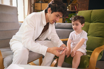 Dad shows his wristwatch to his son, who looking at it with fascination, in a warm and inviting...