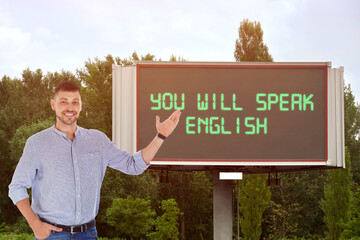 Teacher pointing at text You Will Speak English on digital billboard outdoors. Language course