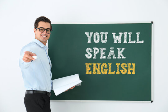 Teacher near green chalkboard with text You Will Speak English. Language course